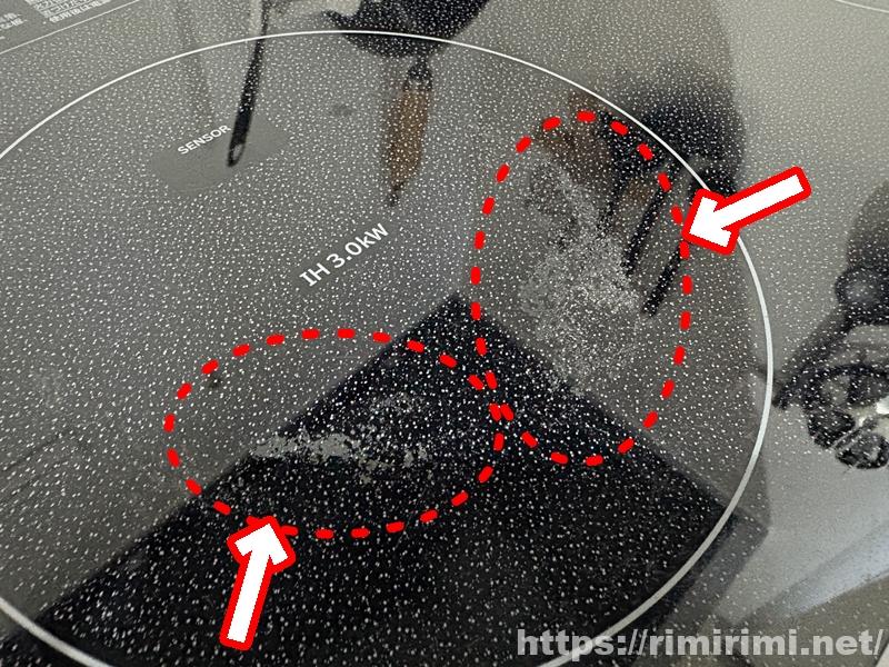 白っぽくザラザラ汚れが残るIHコンロ表面（点線と矢印で表示）