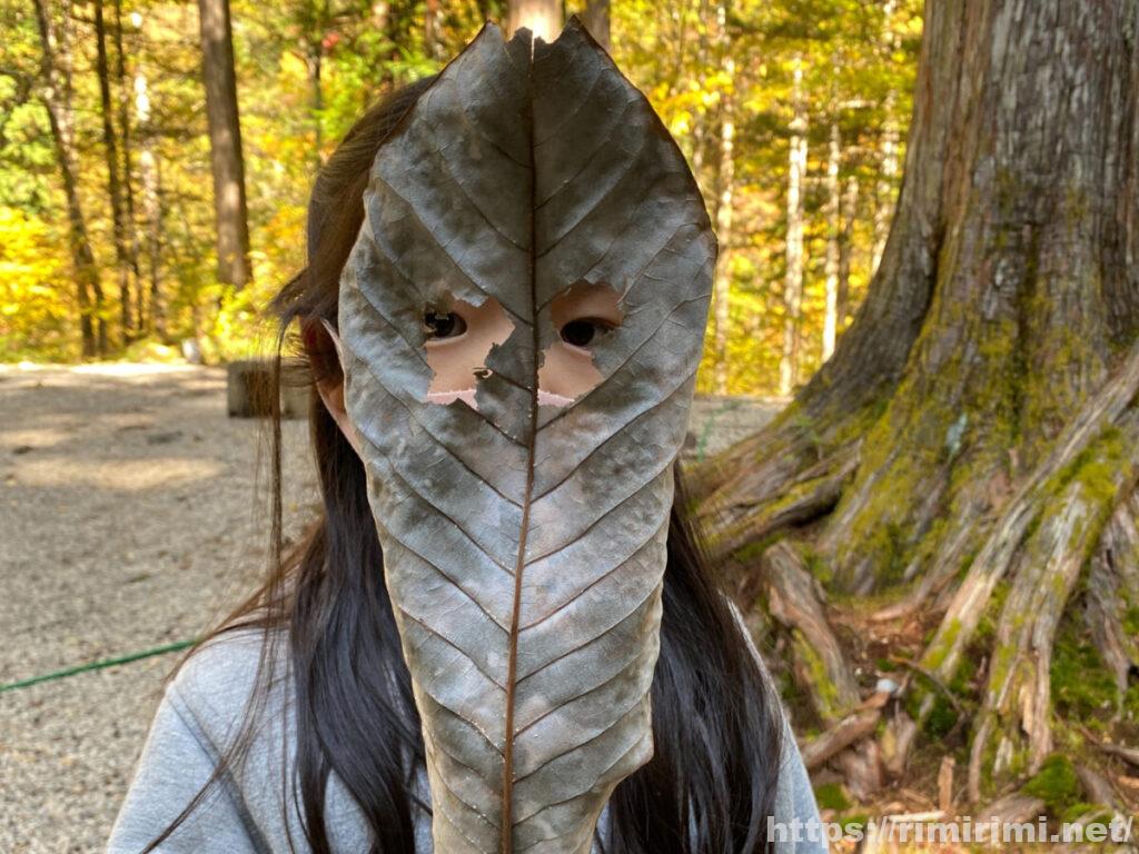 娘が葉っぱのお面を作って遊んでいる写真